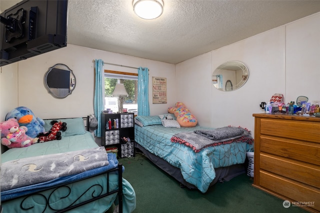 bedroom with a textured ceiling and dark colored carpet