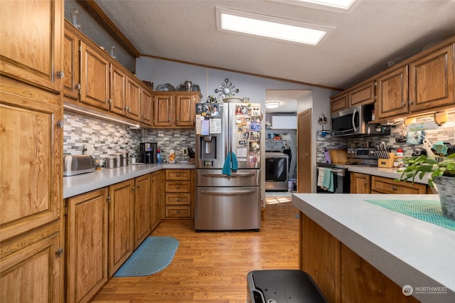 kitchen with tasteful backsplash, ornamental molding, vaulted ceiling, light hardwood / wood-style floors, and stainless steel appliances