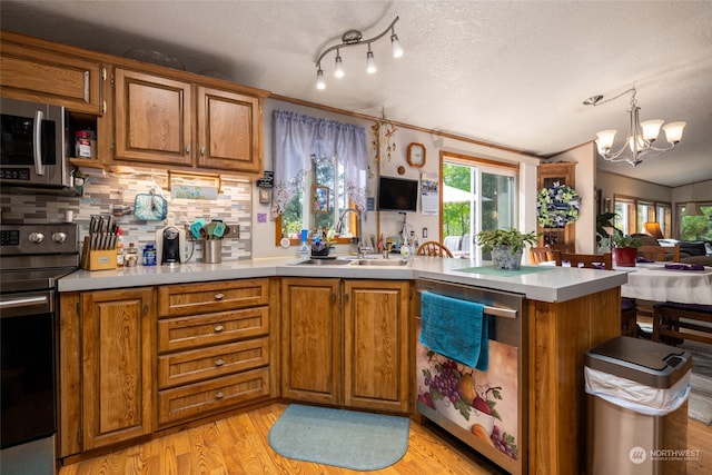 kitchen with sink, appliances with stainless steel finishes, decorative backsplash, a textured ceiling, and kitchen peninsula