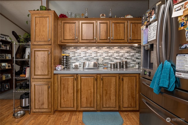 kitchen featuring decorative backsplash, light hardwood / wood-style floors, and stainless steel refrigerator with ice dispenser