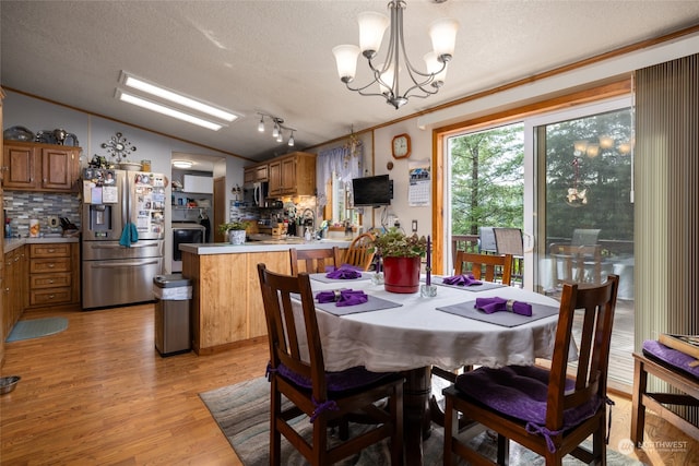 dining space with light hardwood / wood-style floors, rail lighting, a textured ceiling, and lofted ceiling