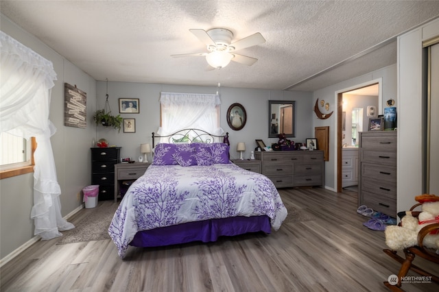 bedroom featuring hardwood / wood-style flooring, ensuite bathroom, multiple windows, and ceiling fan