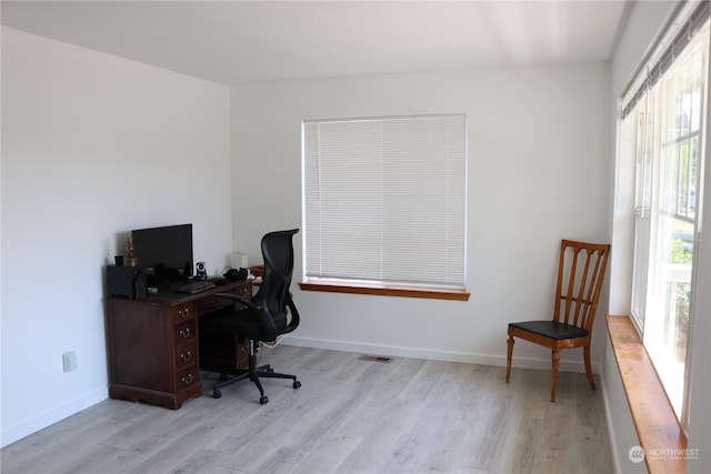 home office with plenty of natural light and light hardwood / wood-style floors