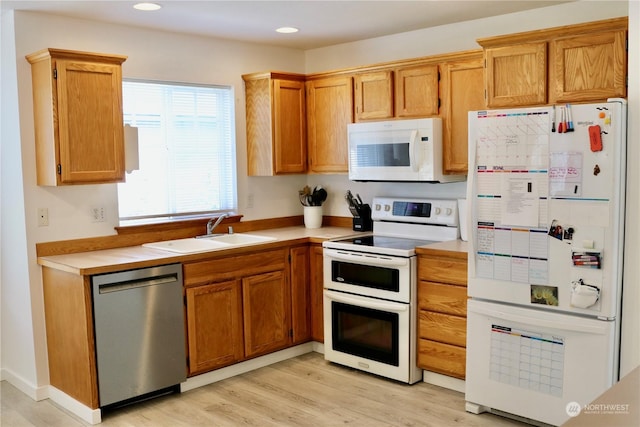 kitchen with sink, white appliances, and light hardwood / wood-style flooring