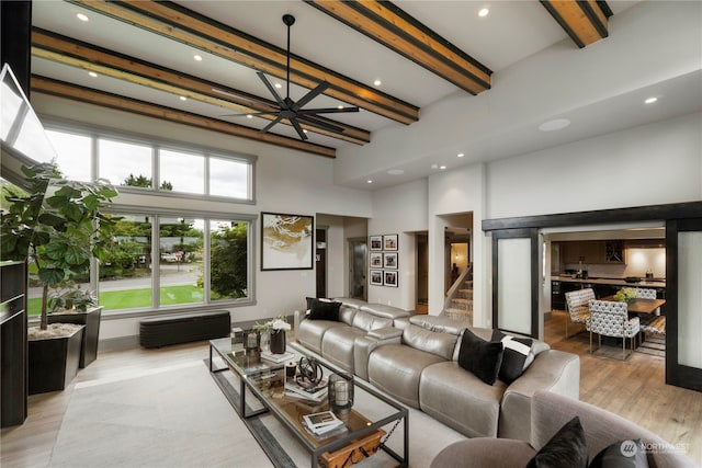 living room featuring beam ceiling, light hardwood / wood-style flooring, and a towering ceiling