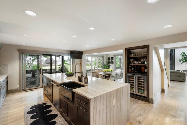 kitchen featuring a center island with sink, light hardwood / wood-style flooring, stainless steel dishwasher, and sink