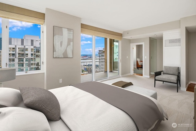 carpeted bedroom featuring access to exterior, baseboards, and a city view