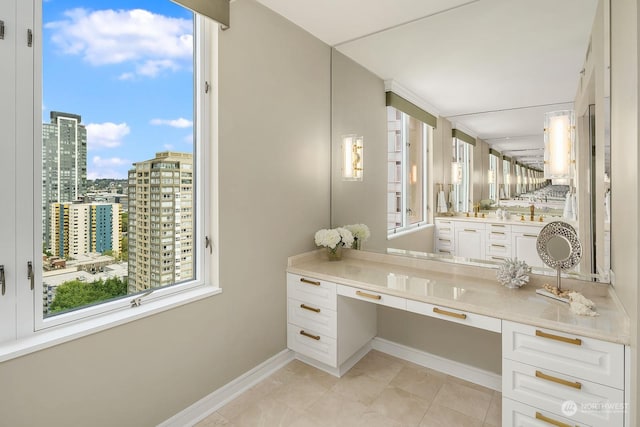 bathroom featuring a view of city, baseboards, vanity, and tile patterned floors