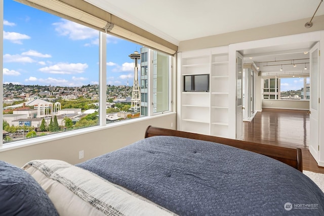 bedroom with track lighting and wood finished floors