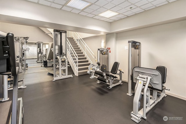 exercise room featuring a drop ceiling and baseboards