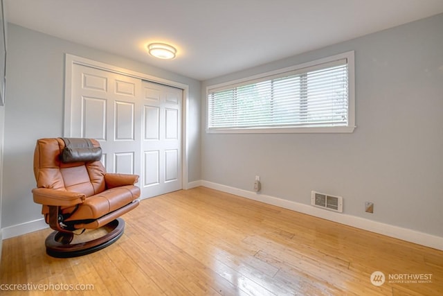 sitting room featuring visible vents, light wood-type flooring, and baseboards