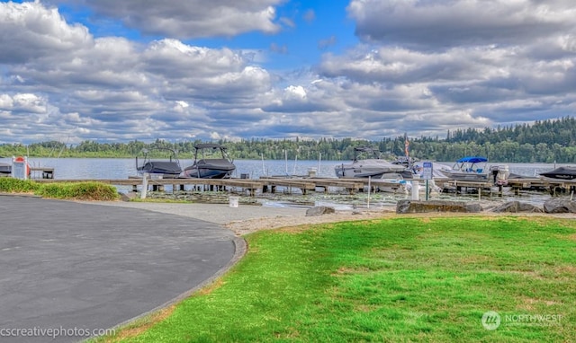 view of dock with a yard, a water view, and boat lift