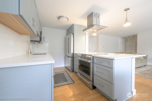 kitchen with a sink, appliances with stainless steel finishes, island range hood, and gray cabinetry