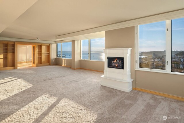 unfurnished living room featuring carpet flooring and a water view