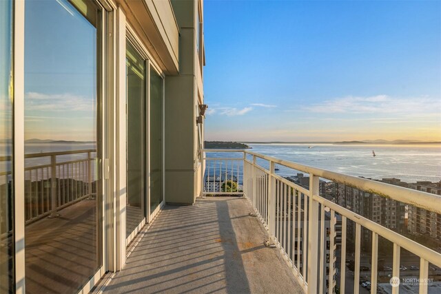 balcony at dusk featuring a water view