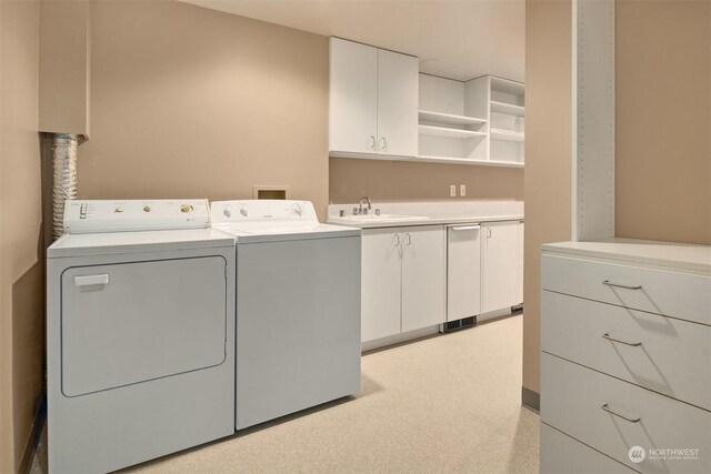 washroom with cabinets, light carpet, washing machine and clothes dryer, and sink