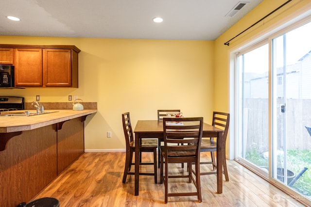 dining room featuring light hardwood / wood-style flooring, sink, and a healthy amount of sunlight