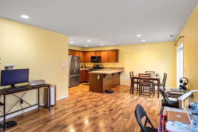 kitchen with sink, kitchen peninsula, light hardwood / wood-style flooring, stainless steel appliances, and a breakfast bar