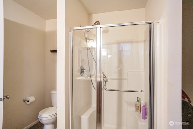 bathroom featuring toilet and a shower with door