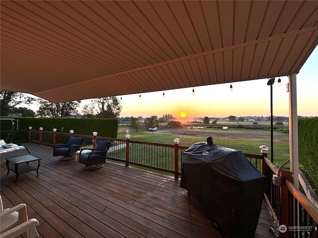 deck at dusk featuring a lawn and a grill