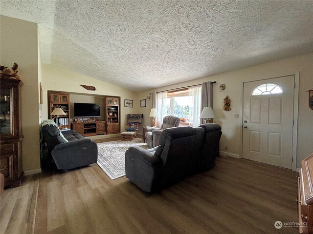 living room featuring hardwood / wood-style floors, a textured ceiling, and lofted ceiling