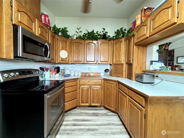 kitchen featuring stainless steel appliances, light hardwood / wood-style flooring, and kitchen peninsula