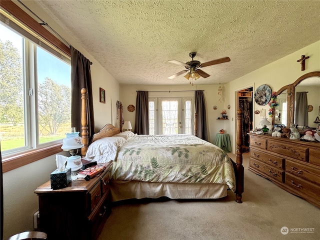 carpeted bedroom with a walk in closet, ceiling fan, a textured ceiling, and multiple windows