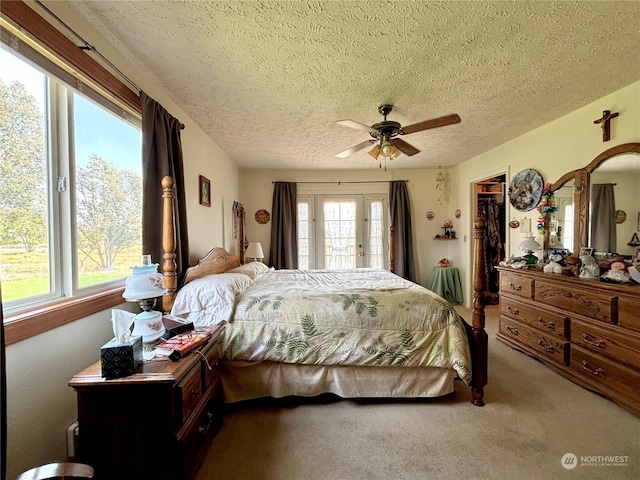 bedroom featuring carpet, a walk in closet, access to exterior, ceiling fan, and a textured ceiling