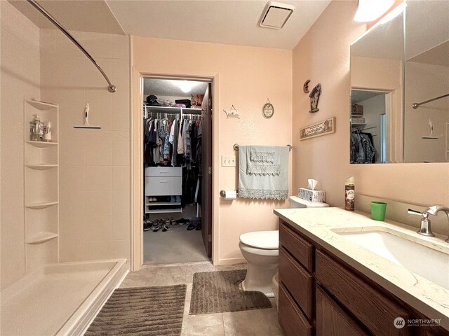 bathroom with tile patterned flooring, toilet, vanity, and walk in shower