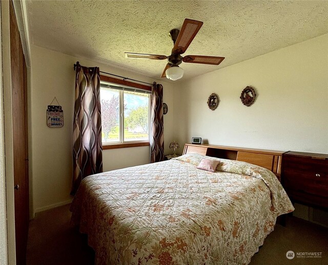 bedroom with dark colored carpet, ceiling fan, and a textured ceiling