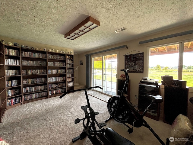 workout room featuring carpet and a textured ceiling