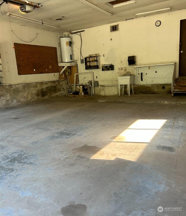 garage featuring a workshop area, a garage door opener, and electric water heater