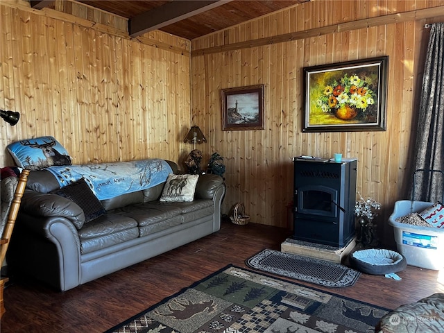 living area with beamed ceiling, wood finished floors, a wood stove, and wooden walls