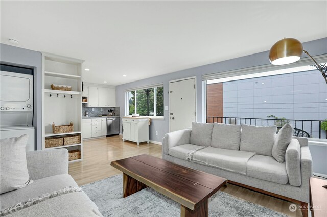 living room featuring stacked washing maching and dryer and light hardwood / wood-style flooring