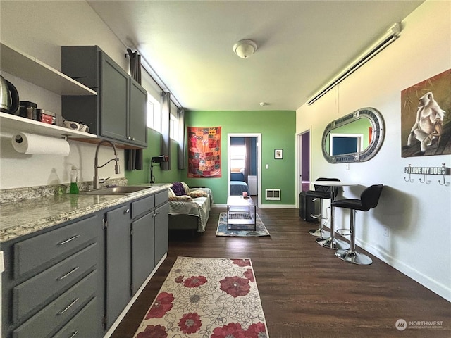 kitchen with sink, dark wood-type flooring, and gray cabinetry