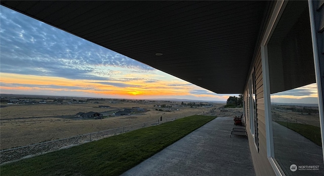 balcony at dusk featuring a rural view