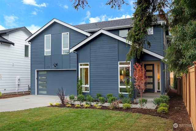 view of front facade featuring a front yard, concrete driveway, a garage, and fence