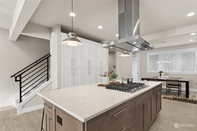 kitchen featuring stainless steel gas cooktop, island range hood, a center island, light wood-type flooring, and pendant lighting