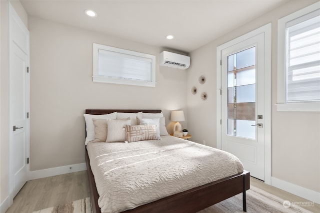 bedroom with a wall unit AC and light hardwood / wood-style floors