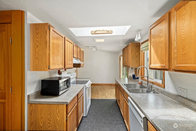 kitchen with stainless steel appliances, a skylight, dark wood-type flooring, and sink