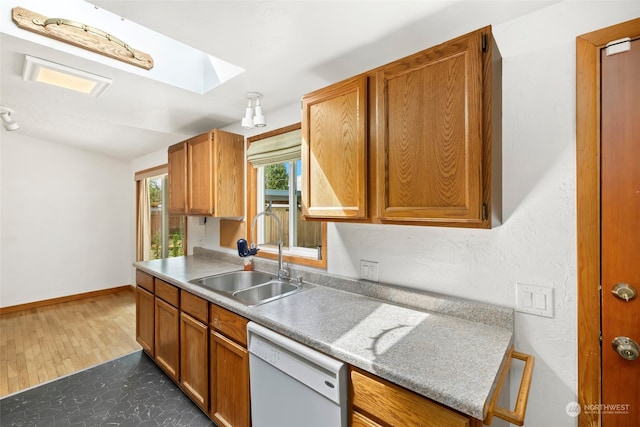 kitchen featuring dishwasher, a skylight, sink, and dark hardwood / wood-style flooring