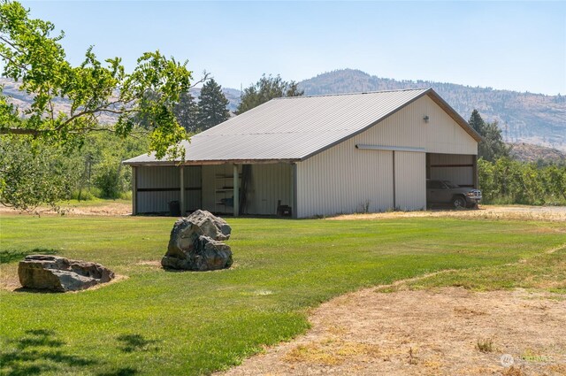 exterior space featuring a mountain view, a detached garage, driveway, a pole building, and a front lawn