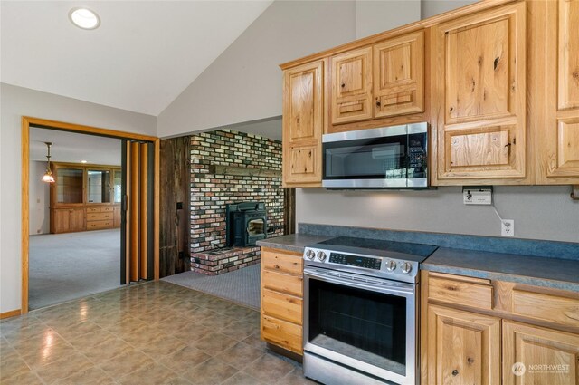 kitchen featuring appliances with stainless steel finishes, dark countertops, light brown cabinets, and lofted ceiling