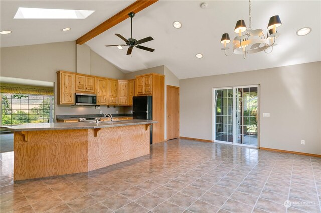 kitchen featuring a skylight, stainless steel microwave, hanging light fixtures, freestanding refrigerator, and beamed ceiling