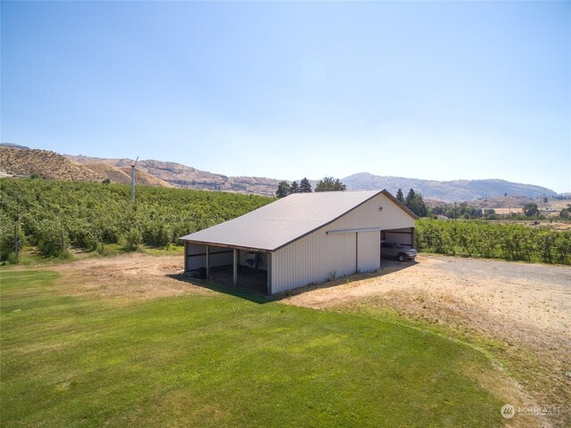 view of pole building with a mountain view, a lawn, and a rural view