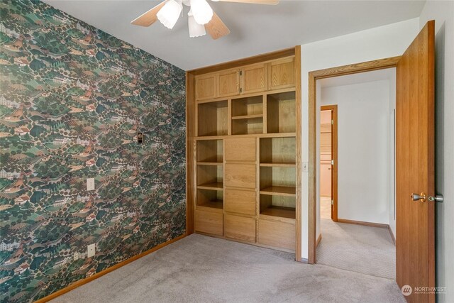 unfurnished bedroom featuring a ceiling fan, light carpet, baseboards, and wallpapered walls