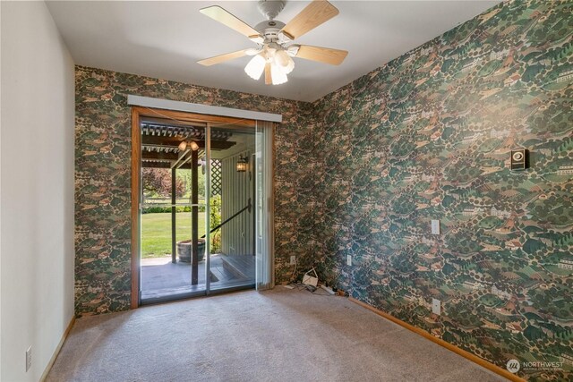 carpeted empty room with ceiling fan and wallpapered walls