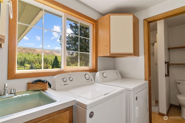 laundry area featuring separate washer and dryer, plenty of natural light, a sink, and a mountain view