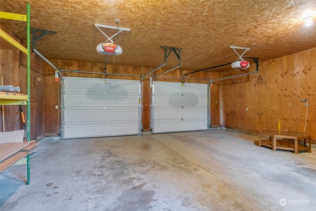 garage with a garage door opener and wood walls