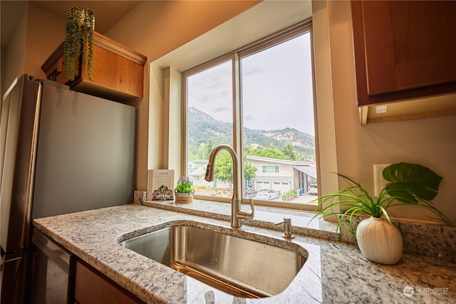 kitchen with appliances with stainless steel finishes, sink, light stone counters, and a mountain view